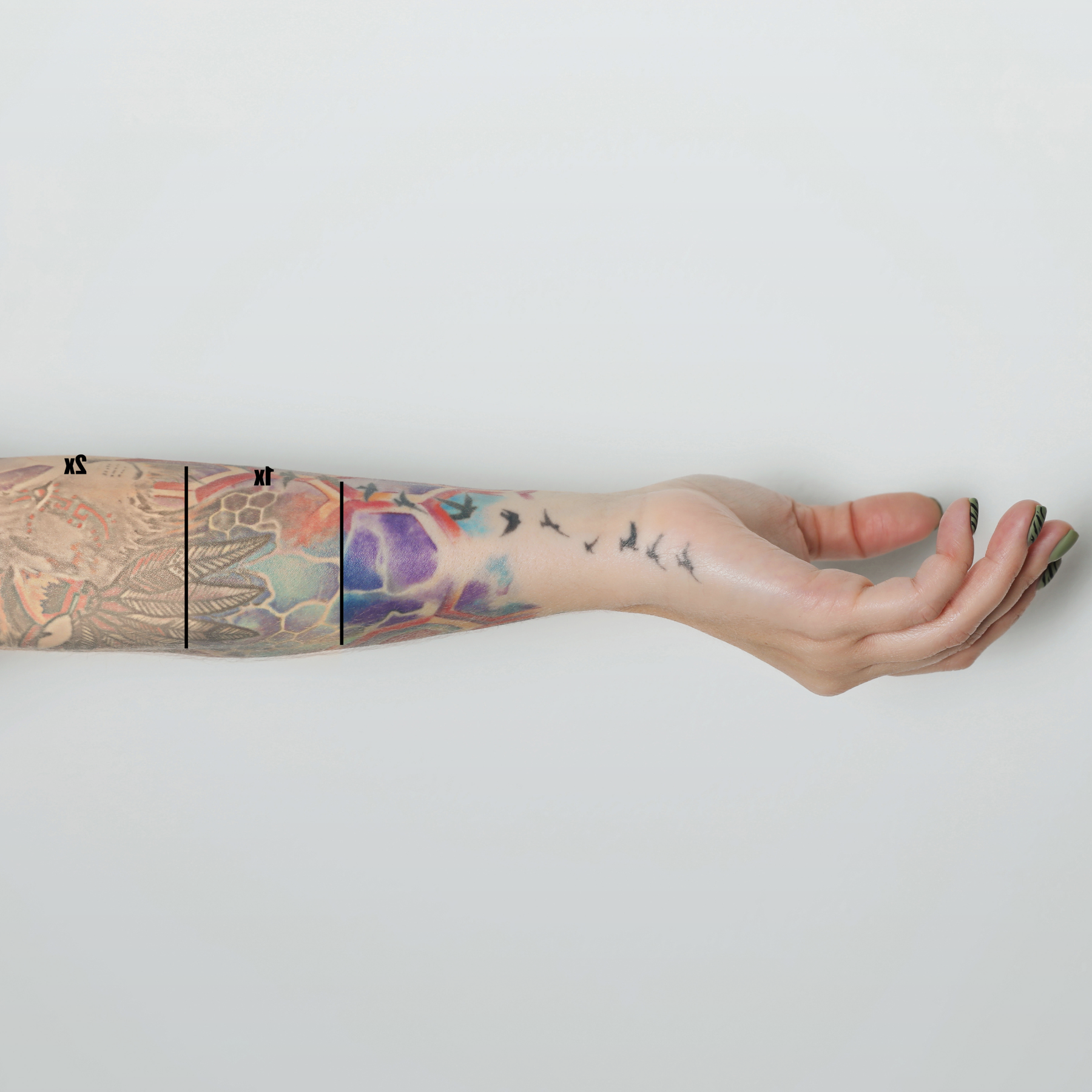 A forearm with a colorful tattoo sleeve is divided into sections, illustrating different stages of laser removal, from dark and vibrant ink to a nearly bare wrist with only faint bird silhouettes remaining.